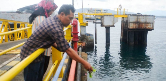 Suryani dan suami, Ahmad, keluarga korban kapal tenggelam KMP Tunu Pratama Jaya melakukan tabur bunga dari atas Dermaga Pelabuhan Ketapang, Banyuwangi, Jawa Timur, Sabtu (5/7/2025). [X]