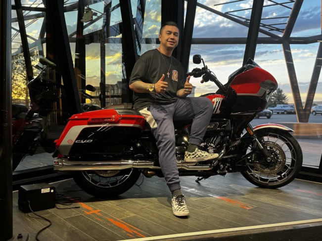 Kevin Wazeng berpose di atas motor dengan kalung salib di dada. (Instagram/@kevinwazeng)