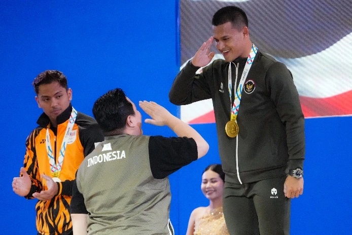 Lifter andalan Indonesia, Letda TNI Rizki Juniansyah, memberikan hormat kepada Menpora Erick Thohir usai menyumbang medali emas cabang olahraga angkat besi kelas 79 kg putra SEA Games 2025, Senin (15/12). [Dok. Kemenpora]