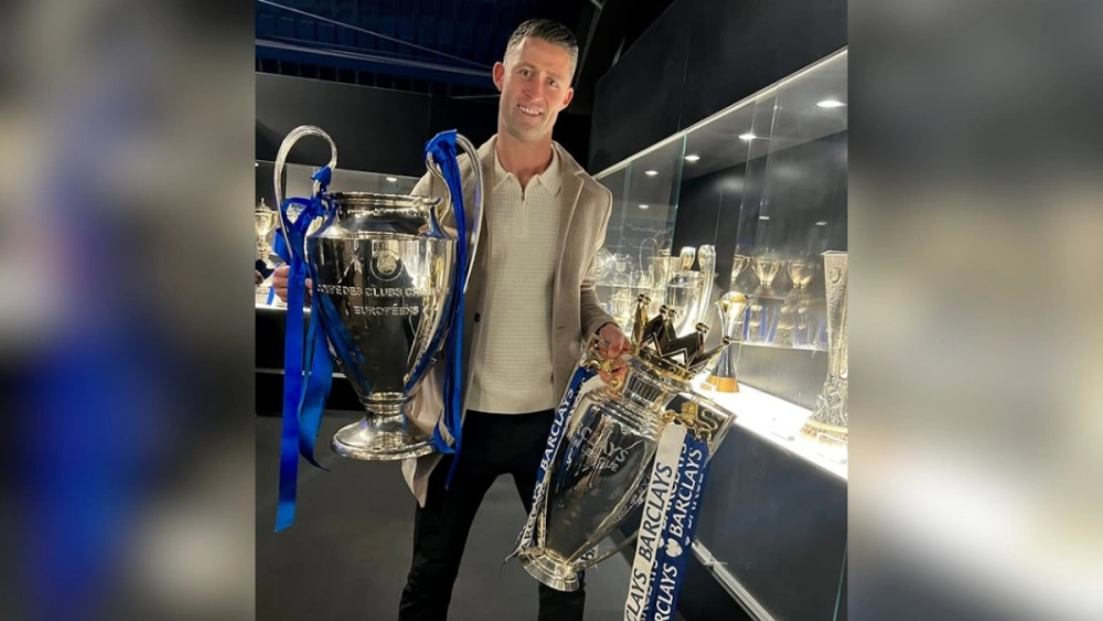 Gary Cahill memegang trofi Liga Champions dan Liga Inggris yang didapatnya saat berseragam Chelsea. [Ist]