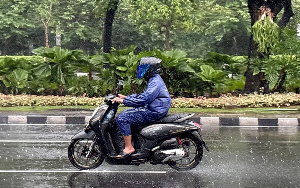 Ilustrasi pemotor memakai jas hujan saat hujan lebat. [Ist]