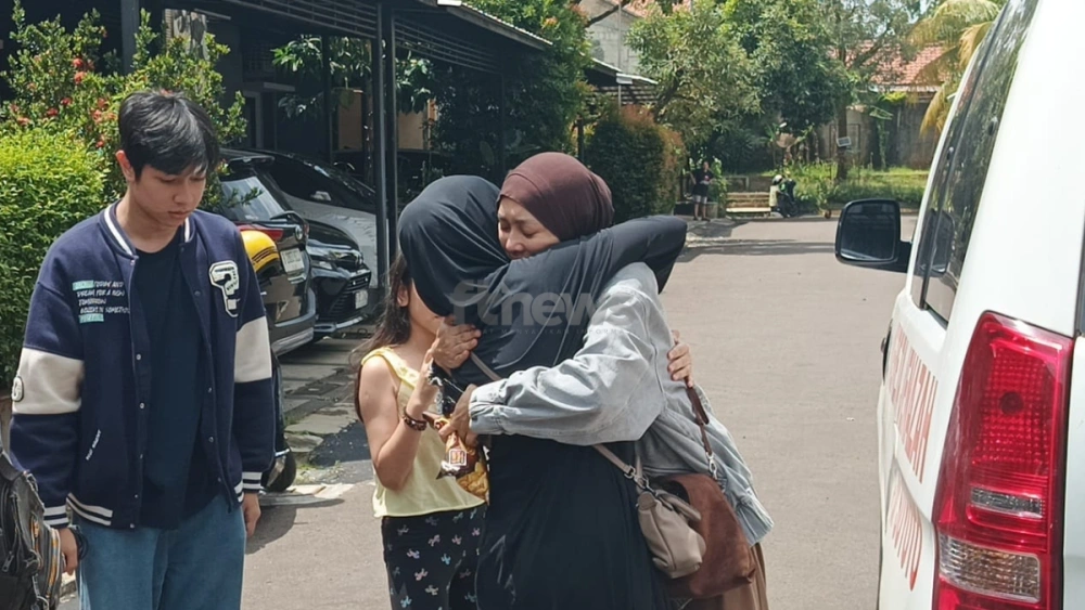 Istri Gary Iskak tak kuasa menahan tangis di pelukan seorang warga yang melayat, Sabtu (29/11/2025). [FTNews.co.id/Selvianus Kopong Basar]