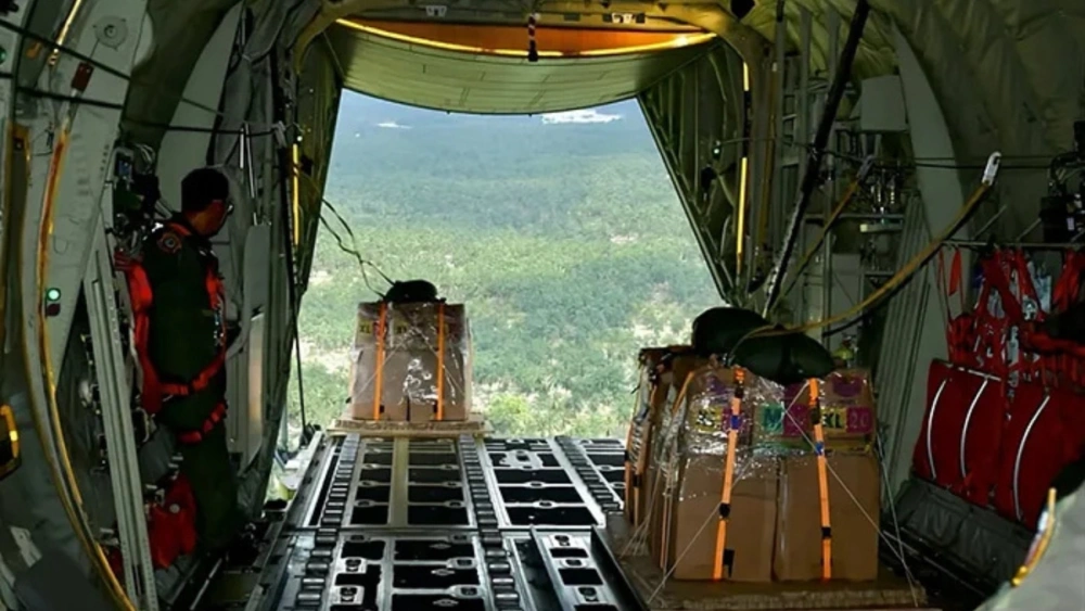 Personel TNI Angkatan Udara menerjunkan bantuan kemanusiaan bencana alam Sumatera melalui airdrop dengan pesawat Super Hercules C-130J di atas langit Kabupaten Aceh Tamiang, Aceh. [Foto: TNI AU]