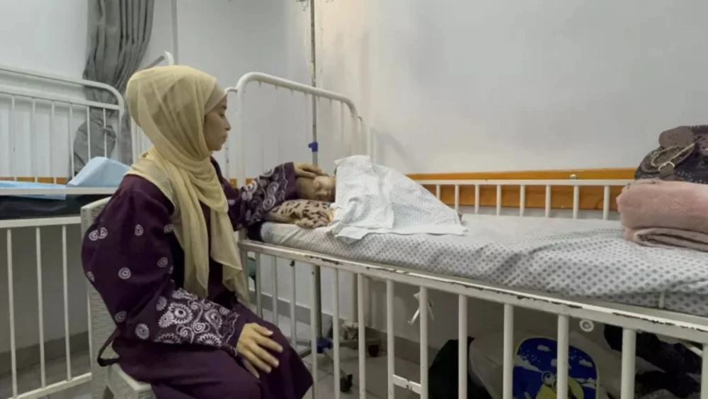 Nesma Ayed duduk di samping tempat tidur putrinya yang berusia 9 tahun, Jana, di Friends of the Patient Society Hospital di Kota Gaza, Jalur Gaza, pada Senin, 25 Agustus 2025.  [UNICEF/UNI854997/Eleyan] 