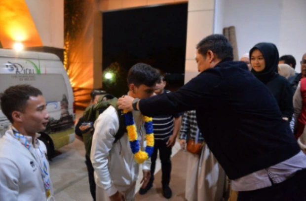 Sekretaris Daerah Riau, Syahrial Abdi, mengalungkan bunga pada Abiyu Raffi menyambut kedatangannya dengan sukacita [Foto: mediacenter.riau]